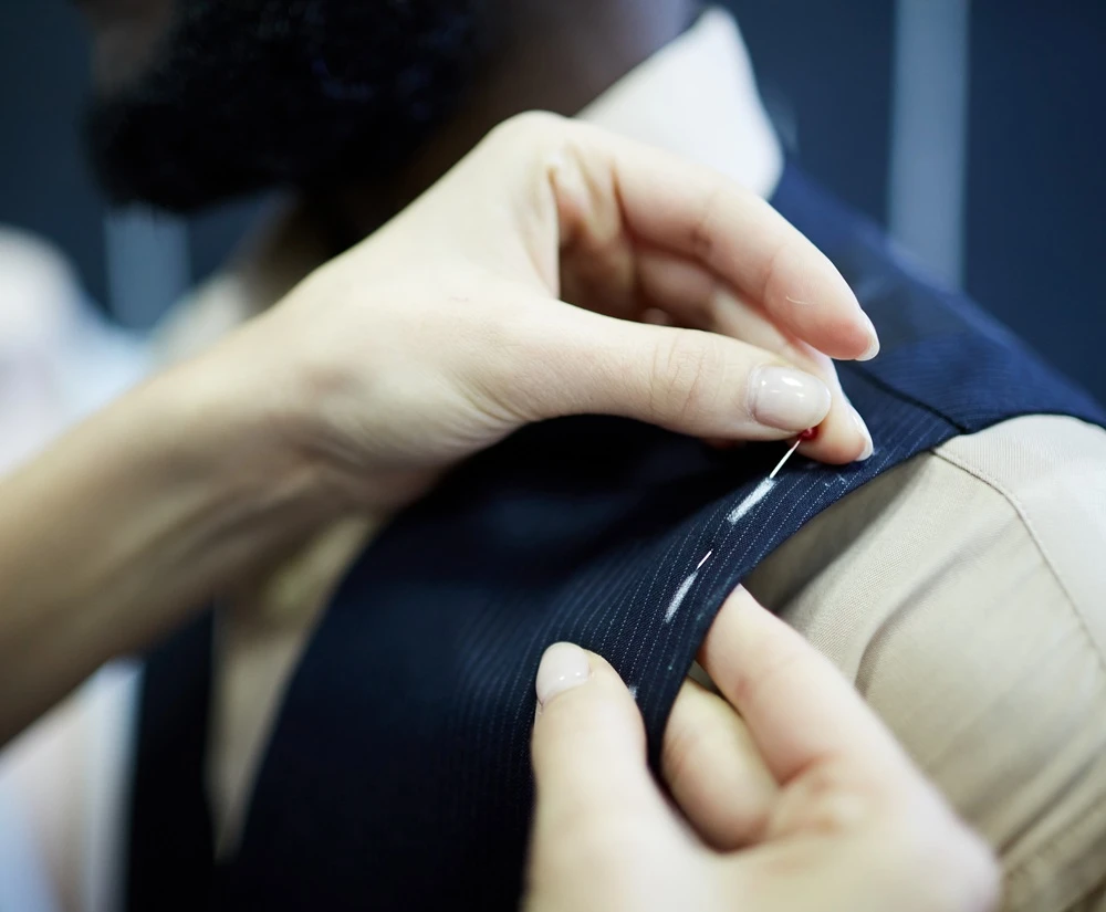 Tailor using sewing pins to fix fabric