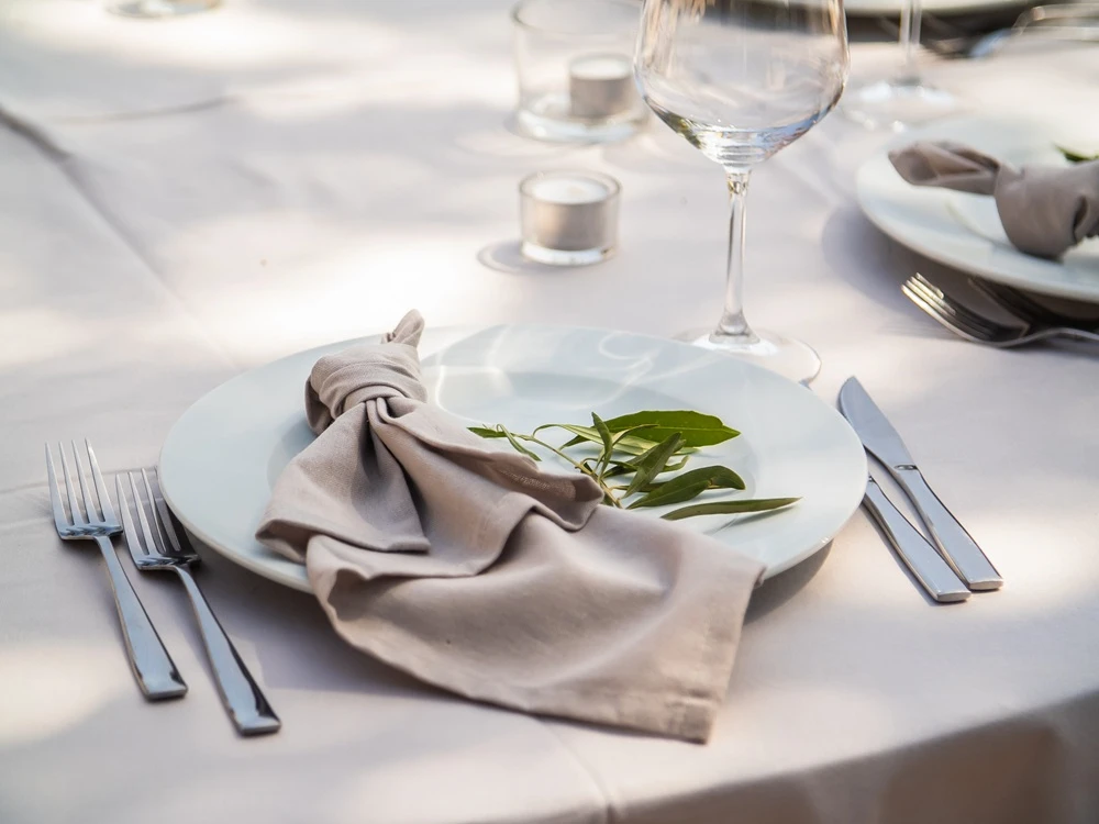 Beautiful outdoor wedding decoration in city. Candles and dried flowers and accessories with bouquets and glasses on table with linen tablecloth on newlywed table on lawn